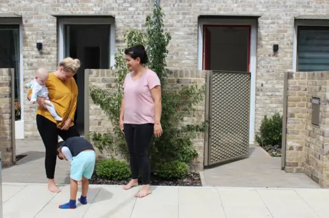 BBC Two mothers and their children stand outside their houses