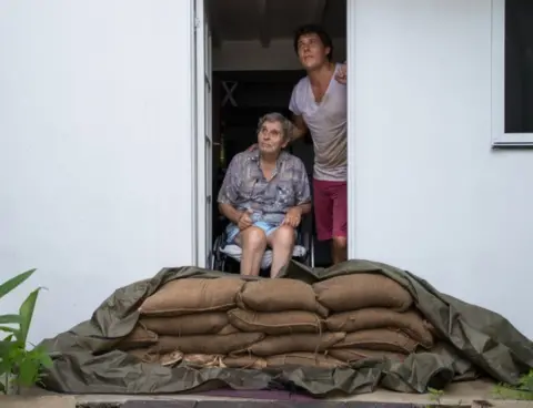 EPA Parramatta Park resident John Irving and his son Steve look at the sky from their sandbagged doorway in Cairns, Queensland, on 15 December 2018.