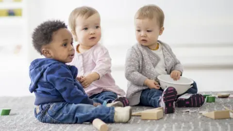 Getty Images Three nursery-aged children sit playing