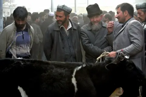 Getty Images Uighur men gather at a bazaar to sell their sheep in Hotan, in the Xinjiang region