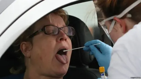 Getty Images Woman takes swab test for coronavirus at Glasgow Airport