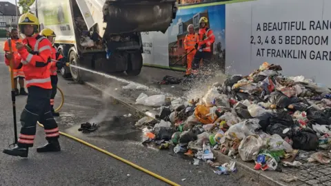 Cambridgeshire Fire and Rescue Firefighters dowsing down refuse fire