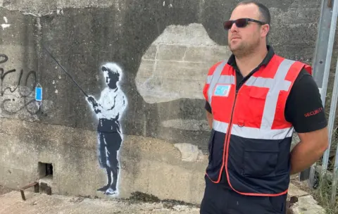 Richard Knights/BBC A security guard protecting a mural in Harwich