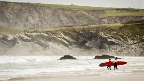 Ben Birchall/PA Wire Surfers at a beach in Newquay, Cornwall