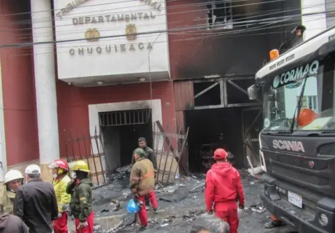 AFP Firefighters work outside the Bolivian electoral office set on fire by protesters on 21 October, 2019.