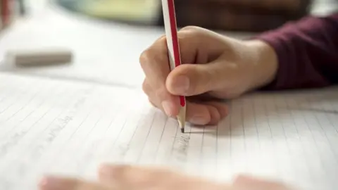 Getty Images A boy writing in a notepad doing his school work