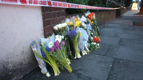 Jonathan Brady/PA Wire Floral tributes left by one of the entrances to Ollgar Close
