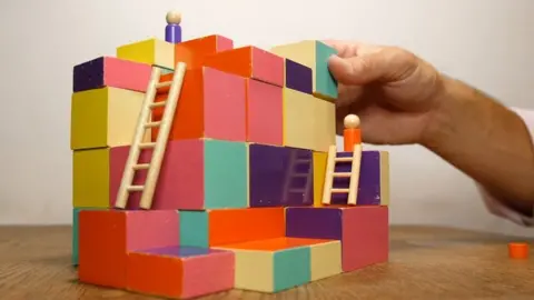 Block game model on table with hand in view