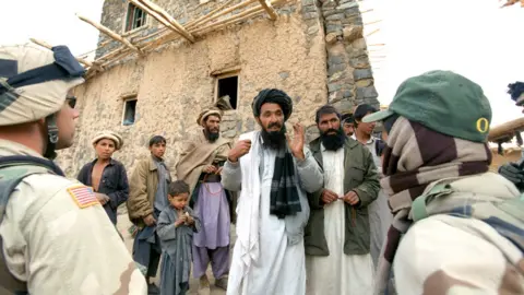 Getty Images An Afghan interpreter (right) helps an American soldier to question local residents in Afghanistan. File photo