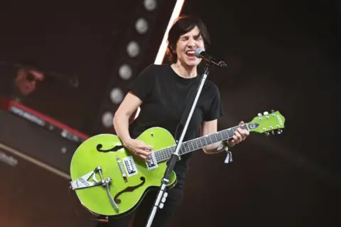 Sharleen Spiteri singing on stage, holding a lime green guitar.