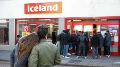 Getty Images Shoppers look at a queue outside Iceland