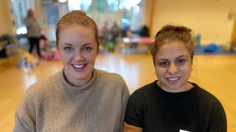 Two women looking at the camera and smiling.