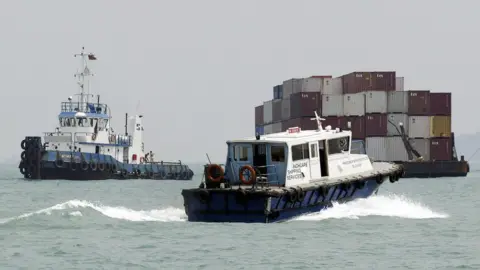 AFP A shipping services boat passes a barge in Singapore