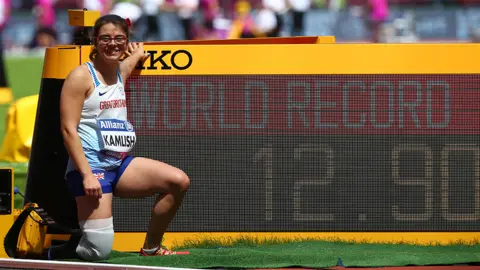 Getty Images Sophie Kamlish, kneeling near a world record board with a trainer and running blade