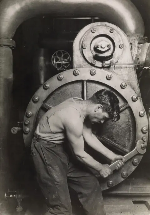 COURTESY OF SWANN AUCTIONS GALLERIES A mechanic uses a spanner on a steam pump.