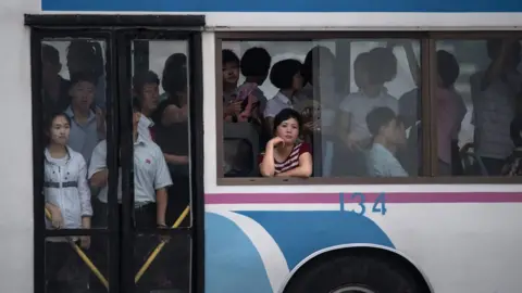 AFP A commuter looks out from the window of a trolley bus tram in Pyongyang on 21 July