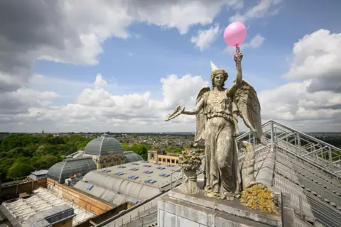 Leon Neal/Getty Images A balloon and party hat on the Angel of Plenty statue at Alexandra Palace, London