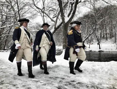 AFP Three people wear American Revolution outfits while walking in snow