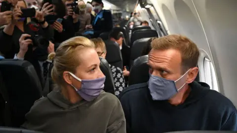 Getty Images Russian opposition leader Alexei Navalny and his wife Yulia sit in a Pobeda airlines plane heading to Moscow before take-off from Berlin Brandenburg Airport (BER) in Schoenefeld, southeast of Berlin, on January 17, 2021.