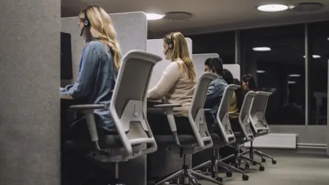 Getty Images male and female customer service representatives sitting on chairs working in call centre