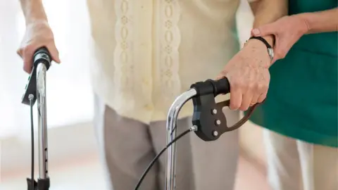 Getty Images A care worker helping an elderly person