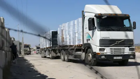 Reuters A lorry carrying goods is seen through a fence after Israel reopened the Kerem Shalom crossing with the Gaza Strip (25 May 2021)