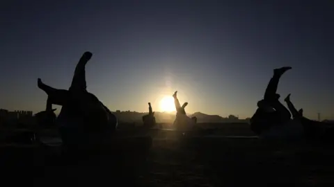 YAHYA ARHAB/EPA-EFE/REX/Shutterstock People perform workouts during sunrise on the first day of 2024, in Sana'a, Yemen