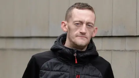 Pacemaker Craig Rowland outside Laganside Court. He has dark hair and wearing a black puffer jacket.