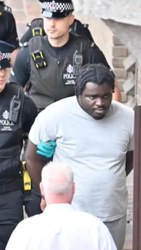 A man being walked in handcuffs.