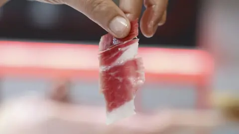 EPA A hand holding a rolled up piece of meat.