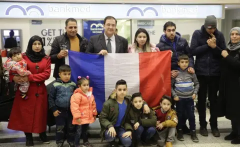 Getty Images The French ambassador to Lebanon poses with Syrian refugees on their way to Paris