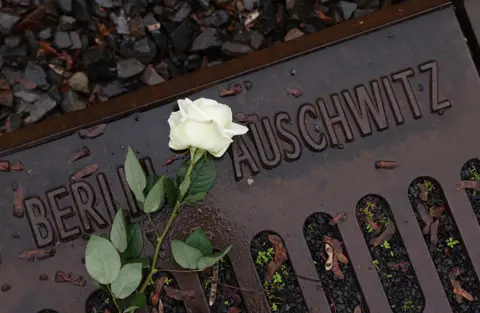 Sean Gallup / Getty Images A flower lies at the railway tracks at the Gleis 17 memorial on Holocaust Remembrance Day on 27 January 2023 in Berlin, Germany