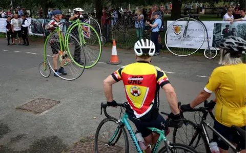 Reuters cyclists watch penny farthing riders prepare