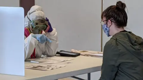 Getty Images Elections Chief Inspector Mary Magdalen Moser runs a polling location in Kenosha, Wisconsin, in full hazmat gear as the Wisconsin primary kicks off despite the coronavirus pandemics on 7 April, 2020