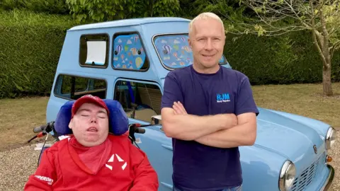 Martin Giles/BBC Robin Middleton and his son Charlie in front of the Pope mobile