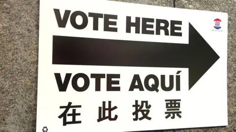 A sign says "Vote here" in English, Spanish and Chinese