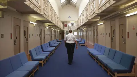 Getty Images A female prison officer walks through the communal area inside HM Prison Styal in Cheshire