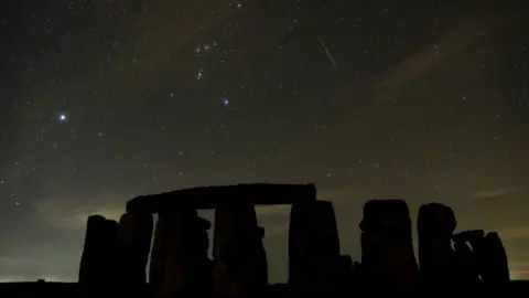 Grant Privett Stars sparkle in the sky above Stonehenge - the trail of one meteor streaks about