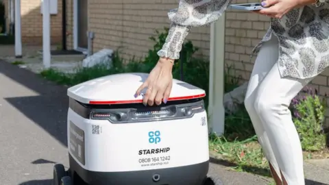 Cambs County Council Woman collecting her goods from a delivery robot