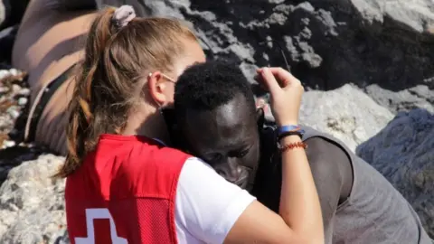 A Spanish Red Cross member hugs a migrant