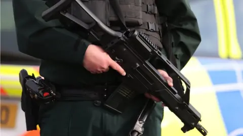 Liam McBurney/PA An armed police officer on duty near the sports complex in Omagh where John Caldwell was shot