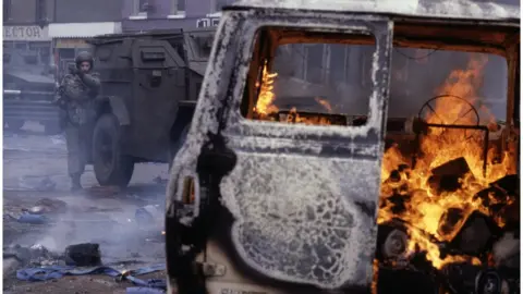 A vehicle burning on a Belfast street circa 1980.