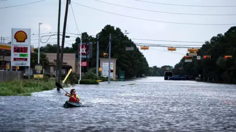 AFP/Getty A woman paddles down a flooded road while shuttling deliveries for her neighbors during the aftermath of Hurricane Harvey on August 30, 2017 in Houston, Texas