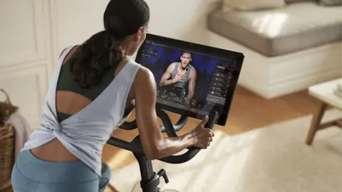 Getty Images A woman uses a Peloton stationary bike