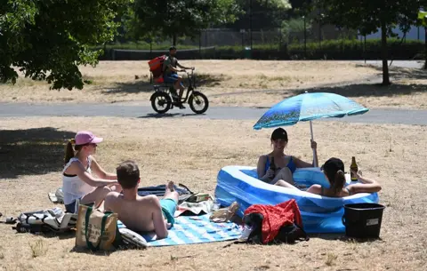 ANDY RAIN/EPA-EFE People in a paddling pool in a park