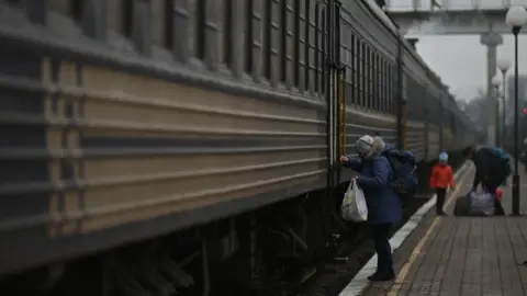 Getty Images A person boards an evacuation train at Kherson station (18 December)