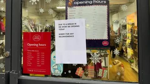 A close-up picture of the sign on the door of the post office, reading "Due to a break-in we won't be opening today. Sorry for any inconvenience"