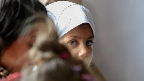 SAMIULLAH POPAL/EPA A girl in a white headscarf looks at the camera