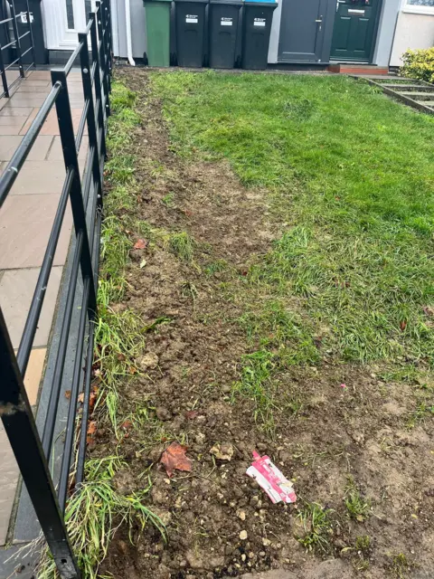 Nicola Haseler/BBC A garden full of green grass, but the left side, near the boundary to a neighbour's garden, is muddy and bare.