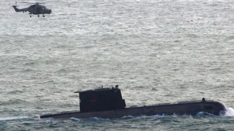 A helicopter flys over a South Africa Navy submarine, following an incident with a South Africa Navy submarine during exercises off Kommetjie in Cape Town, South Africa September 20, 2023